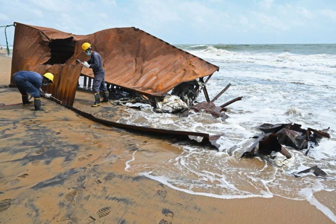 Dos miembros de la Marina de Sri Lanka trabajan sobre los restos de uno de los contenedores que cayeron al mar.