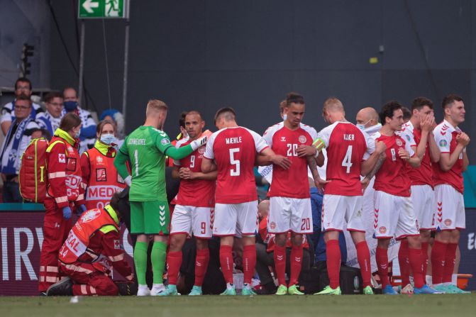 Los jugadores de Dinamarca se reúnen alrededor del mediocampista mientras es atendido por el personal médico.