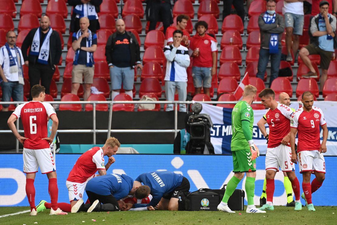 Los médicos atienden al mediocampista danés Christian Eriksen después de que colapsara durante un saque de banda, poco antes del final de la primera parte.