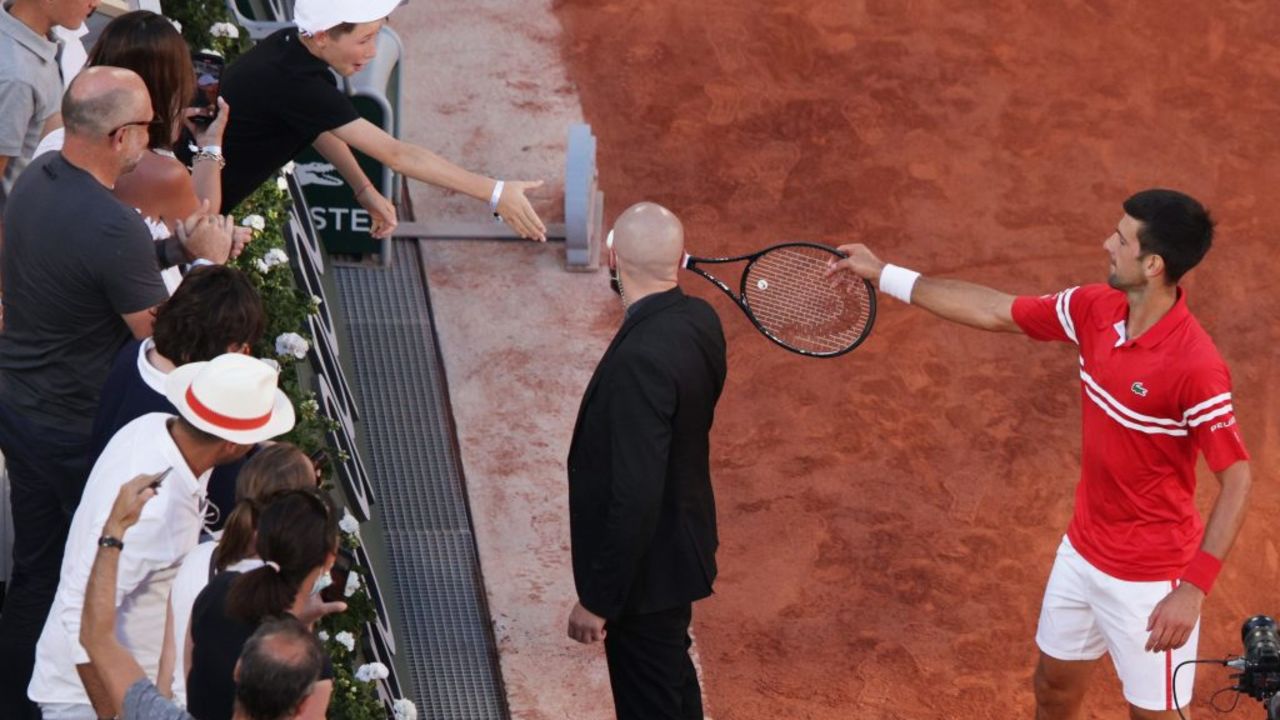 PARIS, FRANCE - JUNE 13: Tournament winner Novak Djokovic of Serbia passes his racquet to a fan as he celebrates after winning his Men's Singles Final match against Stefanos Tsitsipas of Greece during Day Fifteen of the 2021 French Open at Roland Garros on June 13, 2021 in Paris, France.