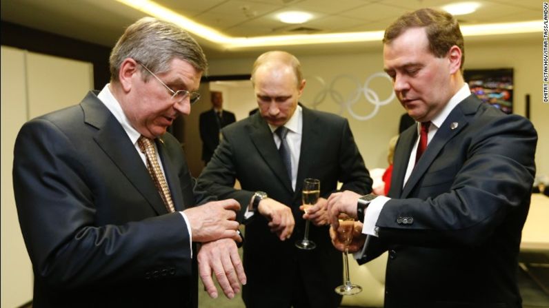 De izquierda a derecha, el presidente del Comité Olímpico Internacional Thomas Bach, Putin y Medvedev miran sus relojes antes de la ceremonia de clausura de los Juegos Olímpicos de Invierno en febrero de 2014. Rusia fue el anfitrión de los Juegos Olímpicos ese año.
