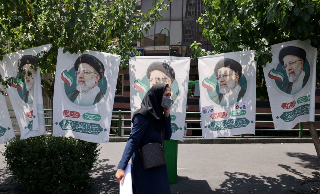 Una mujer camina junto a carteles con la figura del candidato conservador Ebrahim Raisi, el 17 de junio en Teherán, Irán.