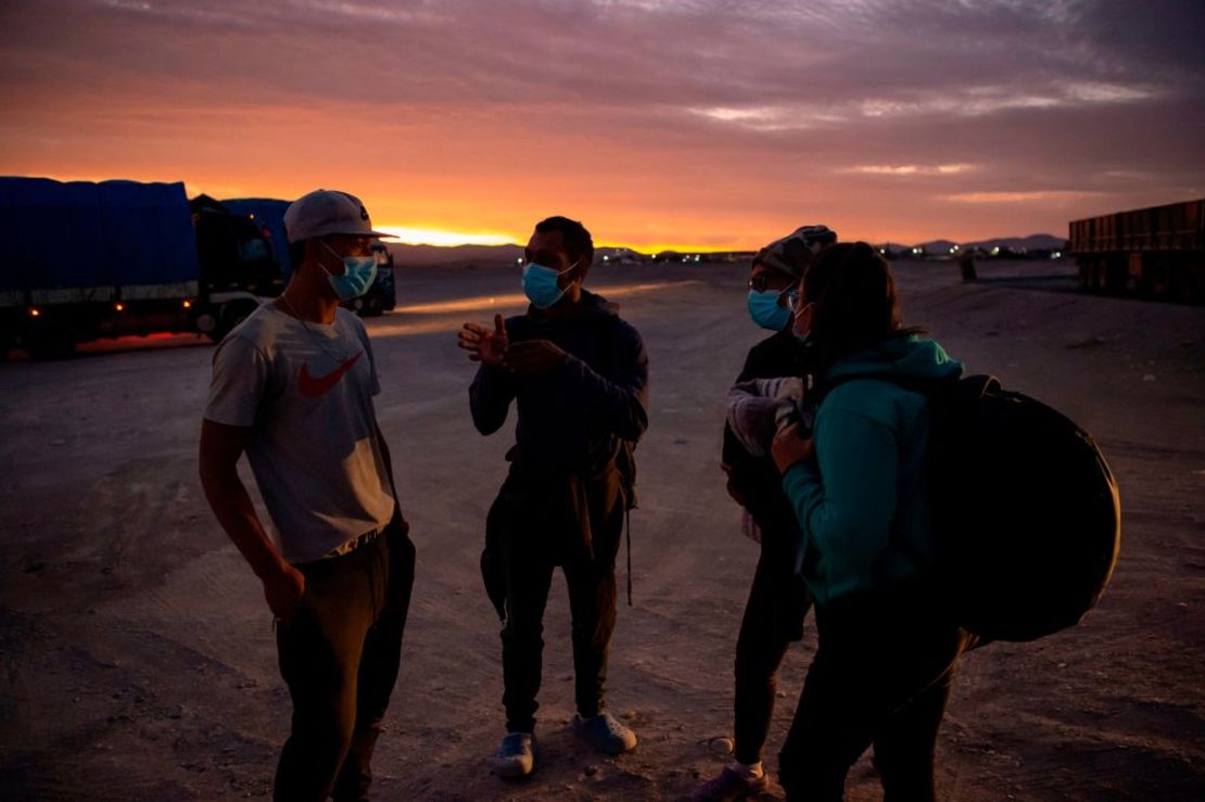 La migrante venezolana Rubi G. (23), Reinaldo, 26, Anyier, 40, y su hija Danyierly, 14 conversan sobre su viaje a Iquique antes de retomar su caminata en Huara, Chile, a 18 de febrero de 2021. Crédito: MARTIN BERNETTI / AFP a través de Getty Images