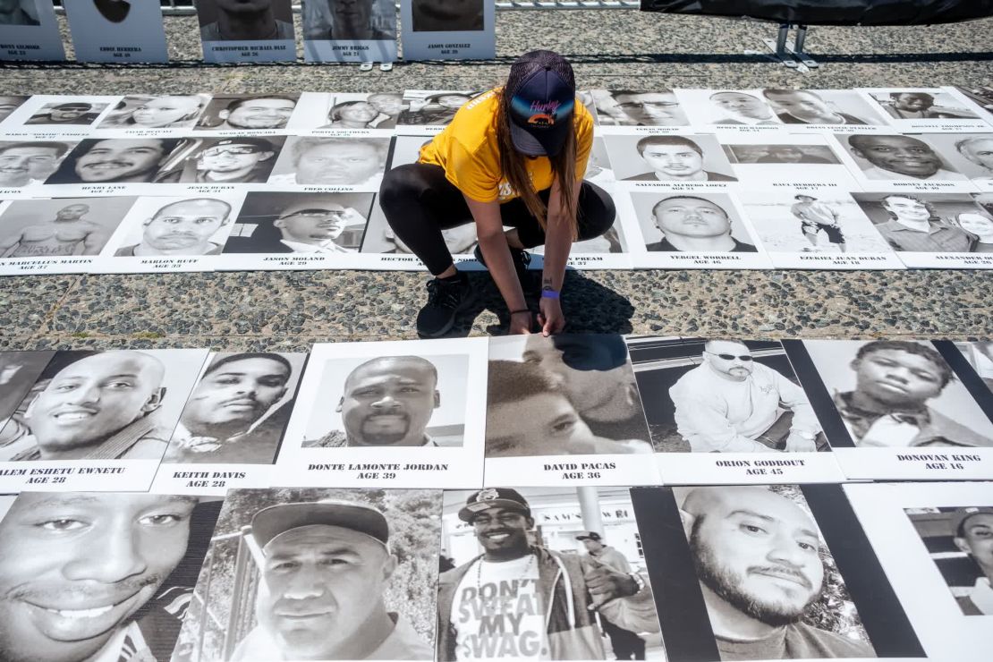 La voluntaria Valerie Vorland coloca decenas de fotografías de personas que murieron a manos de la policía mientras las familias y los activistas se reúnen para una asamblea frente al Ayuntamiento de San Francisco.