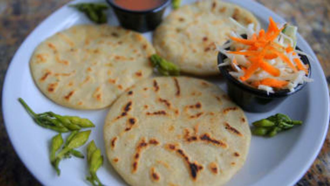 Pupusas servidas con curtido a un lado.