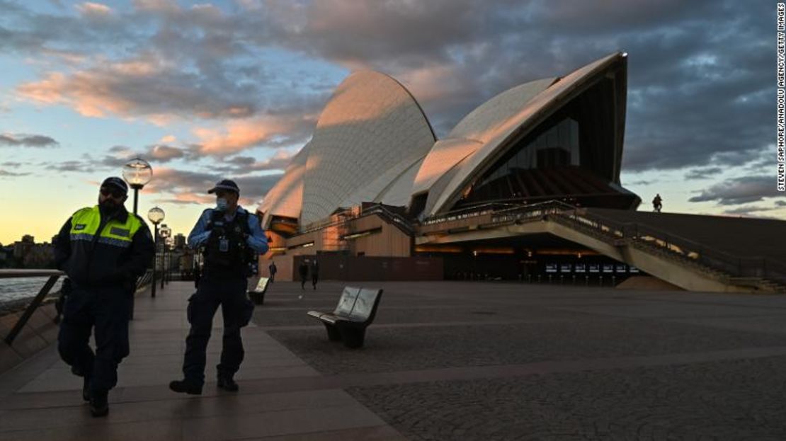 Agentes de policía pasan por la Ópera de Sydney durante el primer día de confinamiento el sábado.