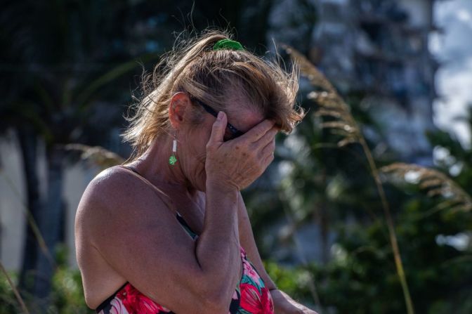 Una mujer llora en la playa, cerca del edificio derrumbado, el 27 de junio de 2021, en Surfside, Florida.