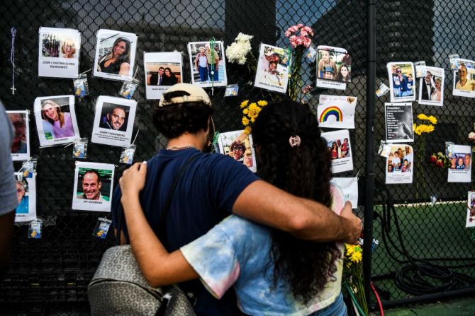Dos personas visitan un homenaje improvisado para las víctimas cerca del lugar del derrumbe en Surfside, Florida, el 27 de junio de 2021.