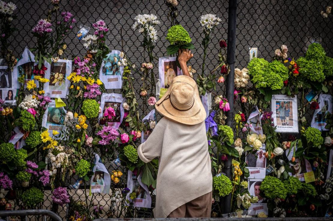 Una mujer agrega flores en un memorial para las víctimas del colapso del edificio en Miami, el 28 de junio de 2021.