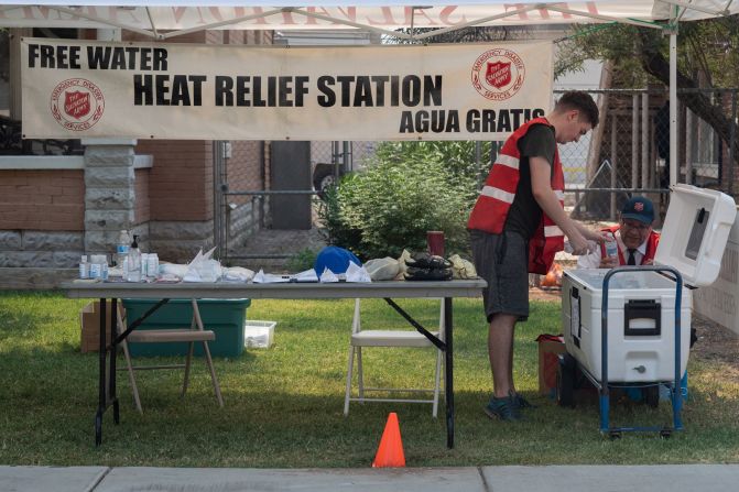 Adrian Keller, a la izquierda, y Tim Smith, llenan una hielera con agua en una estación de alivio de calor del Ejército de Salvación en Phoenix el 15 de junio.