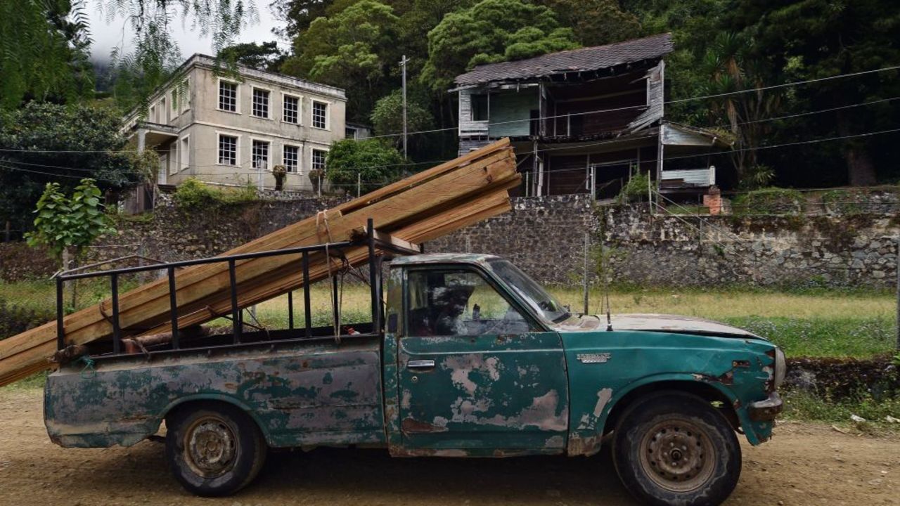 A truck drives past the former US Consulate (L, background) in San Juancito, 40 km northeast of Tegucigalpa, Honduras on February 4, 2020, where US-owned Rosario Mining Company operated gold and silver deposits between 1880 and 1954. - The company extracted 6.5 million tons of mineral valued in 100 million dollars during those 74 years. Nowadays San Juancito is a ghost town which land is still recovering. (Photo by ORLANDO SIERRA / AFP)