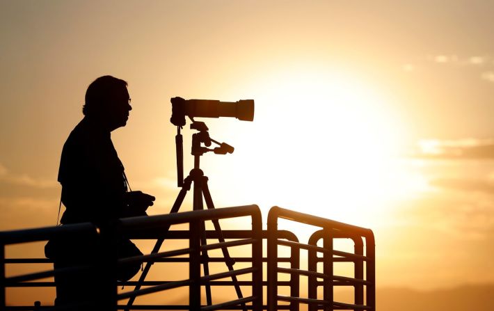 Un fotógrafo prepara su cámara mientras el sol se eleva sobre Spaceport America.