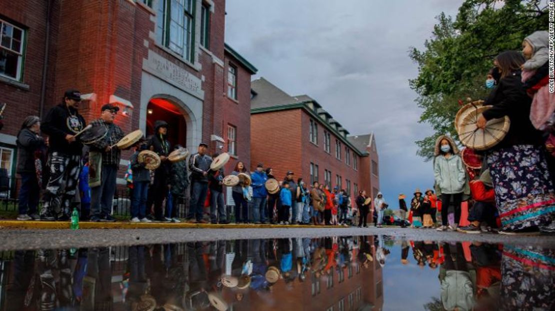 La gente se reúne frente a la antigua escuela de Kamloops para dar la bienvenida a un grupo de corredores de la nación Syilx Okanagan que participan en la carrera Spirit of Syilx Unity Run.