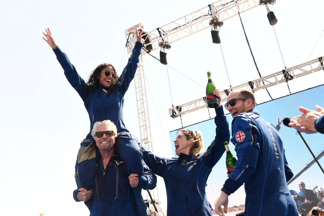 El fundador de Virgin Galactic, Sir Richard Branson, con Sirisha Bandla sobre sus hombros, vitorea con los de la tripulación después de volar al espacio a bordo de una nave de Virgin Galactic, un viaje que describió como la "experiencia de su vida", y que espera que marque el comienzo de un era del lucrativo turismo espacial.