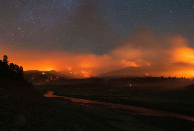 En esta fotografía de exposición larga, tomada a primera hora del 2 de julio, las llamas rodean un lago Shasta afectado por la sequía durante el incendio Salt en Lakehead, California.