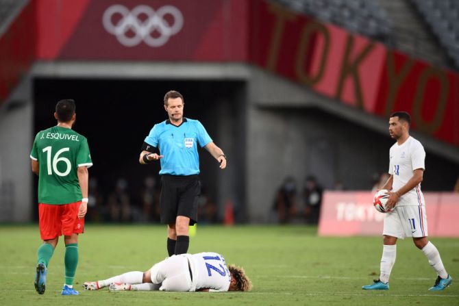 El árbitro australiano Chris Beath chequea el estado del mediocampista de Francia Alexis Beka Beka durante el partido contra México en los Juegos Olímpicos de Tokio.