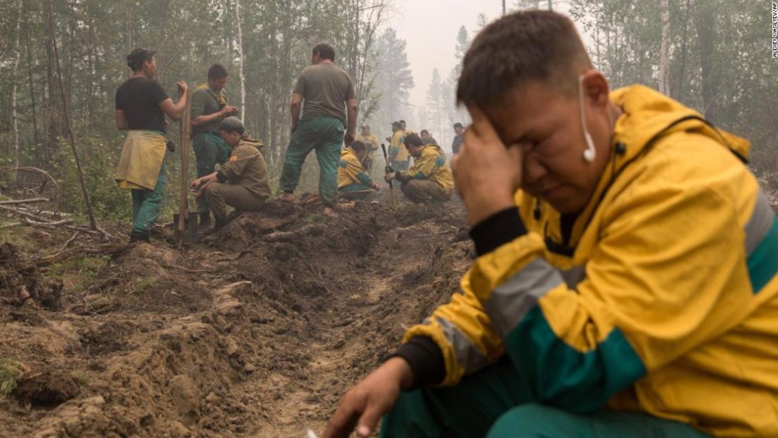 Empleados del servicio de protección forestal Yakutlesresurs descansan mientras cavan una fosa cortafuegos para detener un incendio en las afueras del pueblo de Magaras, en Yakutia.