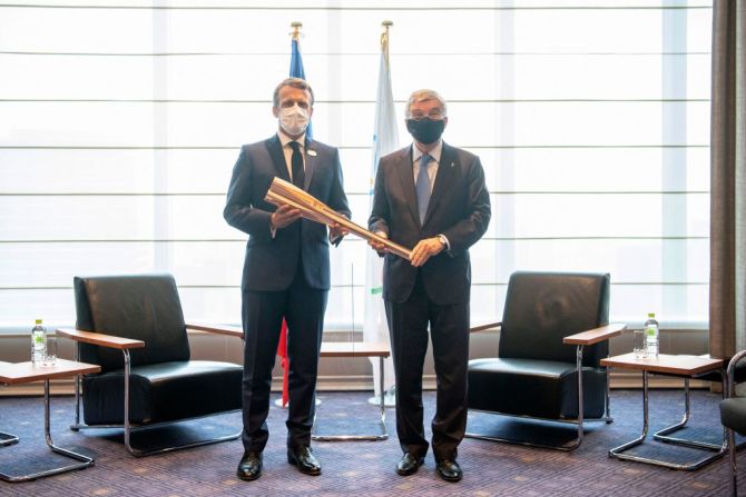 El presidente de Francia, Emmanuel Macron (izq.), recibe la antorcha olímpica de manos del presidente del Comité Olímpico Internacional (COI), Thomas Bach, durante una reunión en Tokio el 23 de julio de 2021, antes de la ceremonia de apertura.