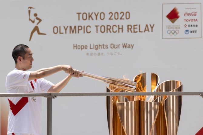 El actor japonés de Kabuki Nakamura Kankuro, portador de la antorcha, pasa la llama olímpica durante la ceremonia de llegada del Relevo de la Antorcha Olímpica.