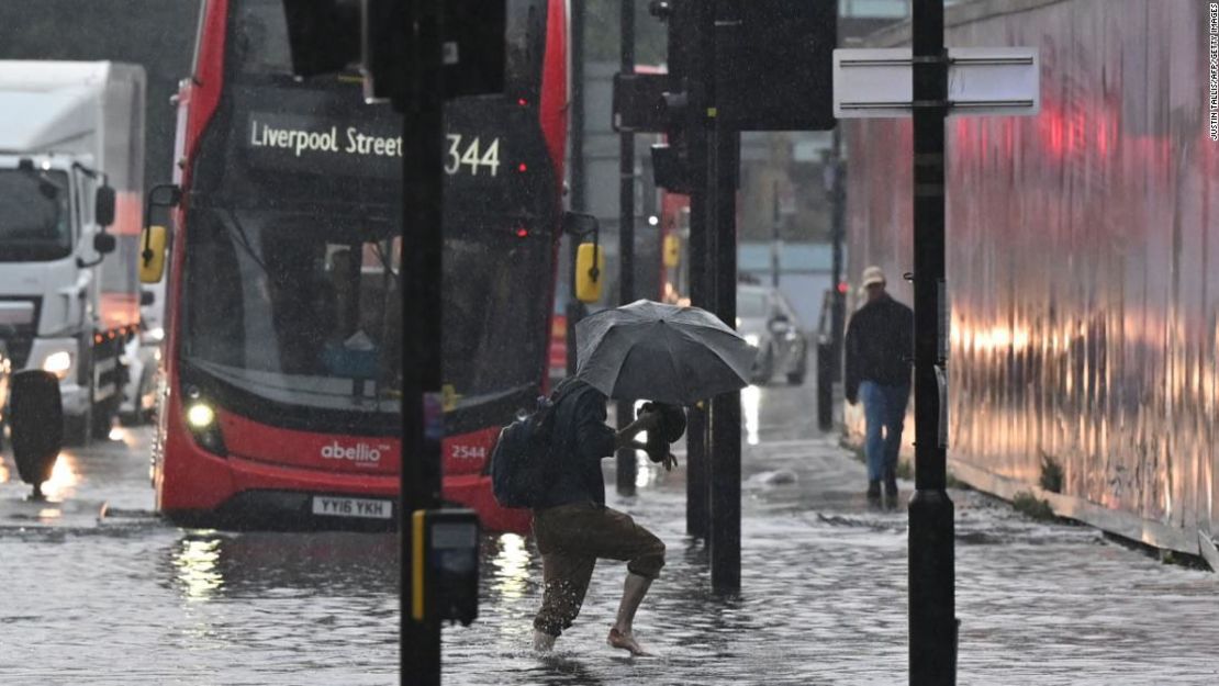 Un peatón cruza a través de aguas profundas en una calle inundada en Londres el 25 de julio de 2021.