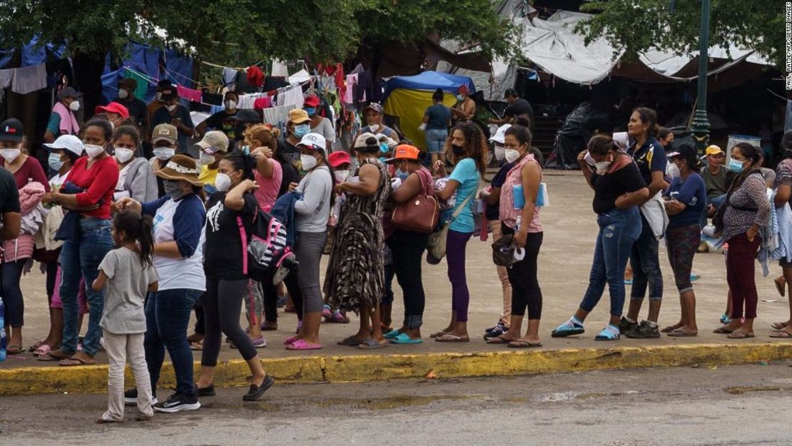 Migrantes que fueron enviados de regreso a México esperan en fila para recibir alimentos y suministros en un campamento al otro lado de la frontera entre Estados Unidos y México en Reynosa, Tamaulipas.