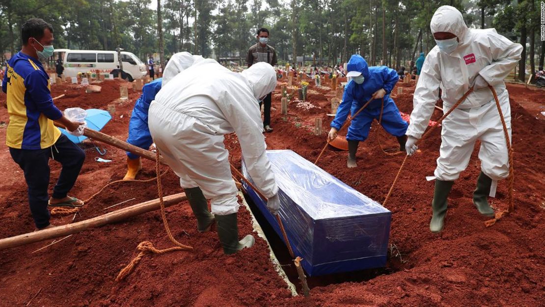 Trabajadores con equipo de protección bajan el ataúd de una víctima del covid-19 a una tumba para ser enterrada en el cementerio de Cipenjo en Bogor, Java Occidental, Indonesia, el 14 de julio de 2021.