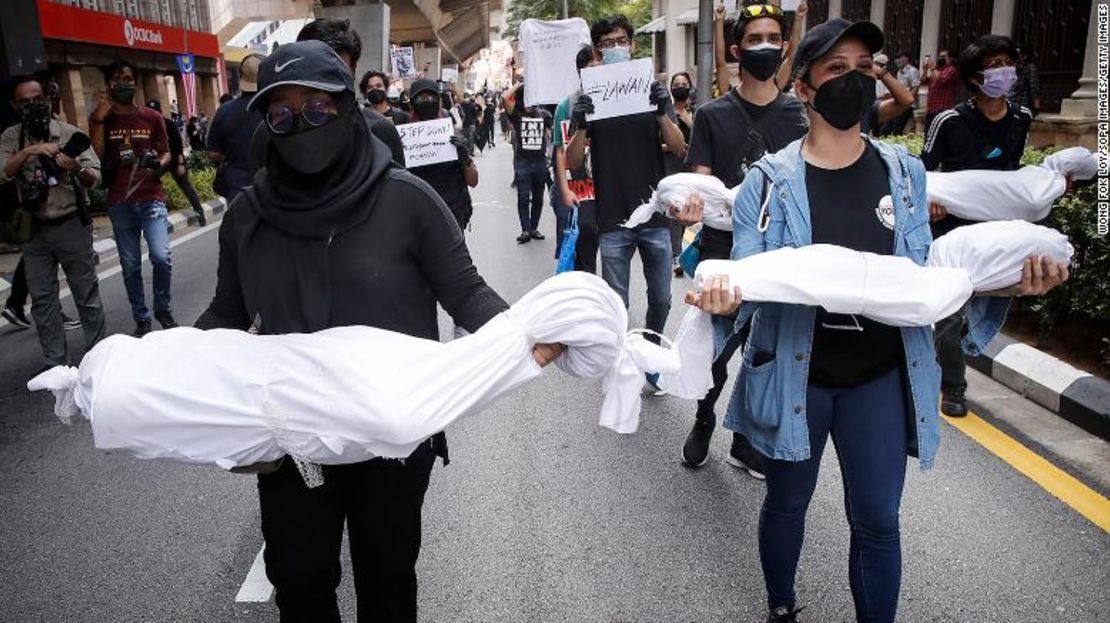 Manifestantes sostienen cadáveres falsos durante una manifestación cerca de la Plaza de la Independencia en Kuala Lumpur, exigiendo la renuncia del primer ministro por su manejo de la pandemia de coronavirus.