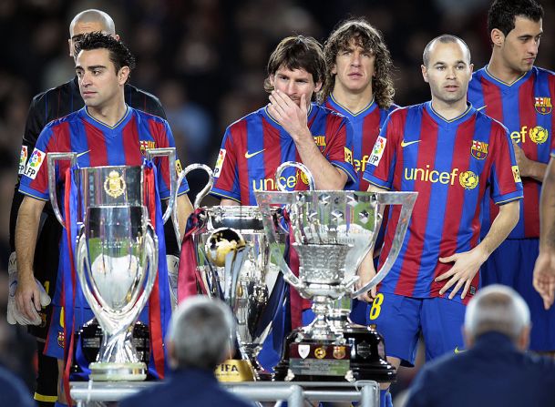Iniesta, Messi, y Puyol frente a los seis trofeos de la temporada 2009.