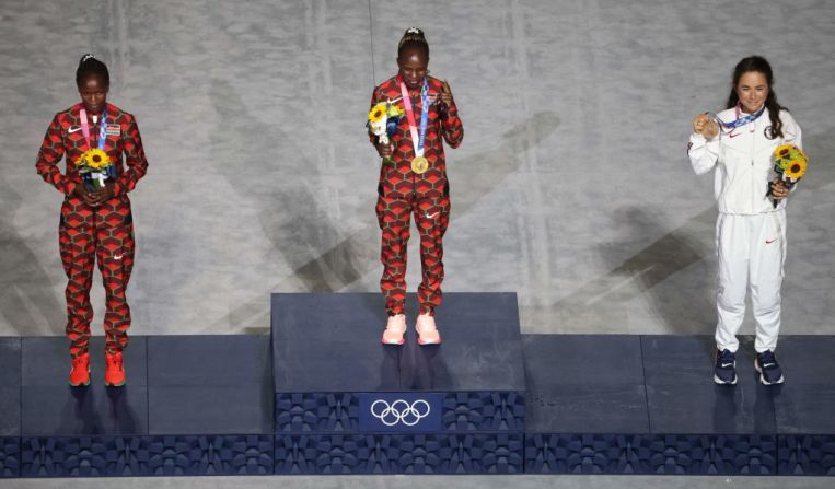 (De izquierda a derecha), la keniana Brigid Kosgei, medalla de plata; la keniana Peres Jepchirchir, medalla de oro; y la estadounidense Molly Seidel, medalla de bronce, suben al podio durante la ceremonia de entrega de medallas del maratón femenino, celebrada durante la clausura de los Juegos Olímpicos de Tokio 2020, el 8 de agosto de 2021 en el Estadio Olímpico de Tokio. Fue una de las dos ceremonias de medalla que ocurrieron en esta clausura.