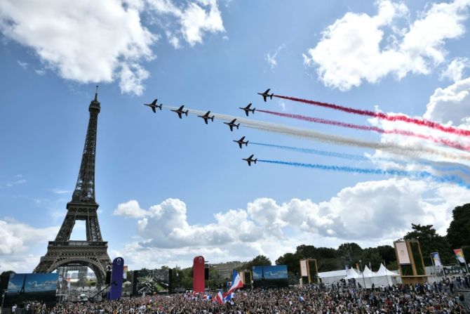 La patrulla aérea francesa 'Patrouille de France' sobrevuela la villa de aficionados de El Trocadero situada frente a la Torre Eiffel, en París, el 8 de agosto de 2021, durante la transmisión de la ceremonia de clausura de los Juegos Olímpicos de Tokio 2020.