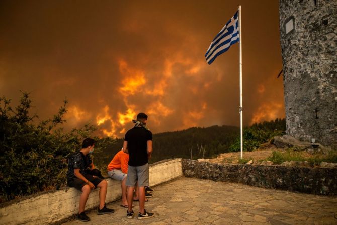 Residentes locales de Gouves, en la isla de Evia, observan como el fuego se acerca a la zona.
