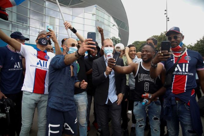 Seguidores de Messi gritan junto a un periodista a las afueras del club Paris Saint-Germain.