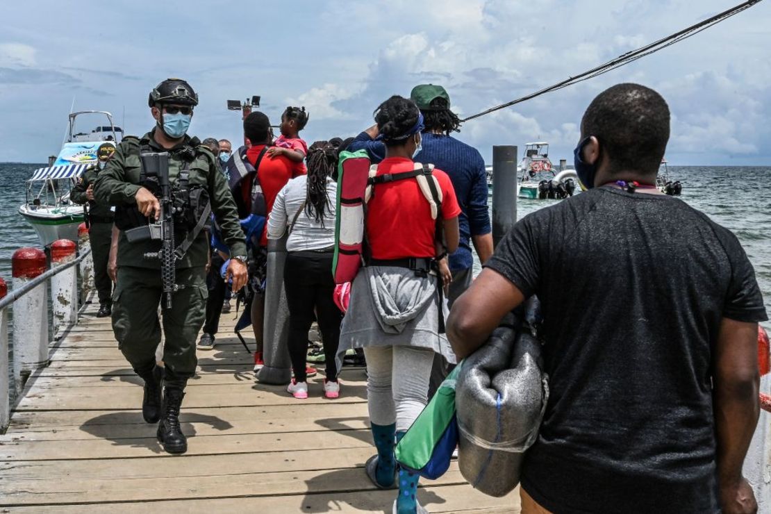 Un policía de Colombia pasa por el lado de migrantes de Cuba, Haití, Venezuela y varios países africanos que buscan dejar Necoclí, Antioquia, en el noroeste de Colombia, el 29 de julio de 2021. Muchos quedaron varados varios días por falta de transporte. Buscan llegar a Estados Unidos.