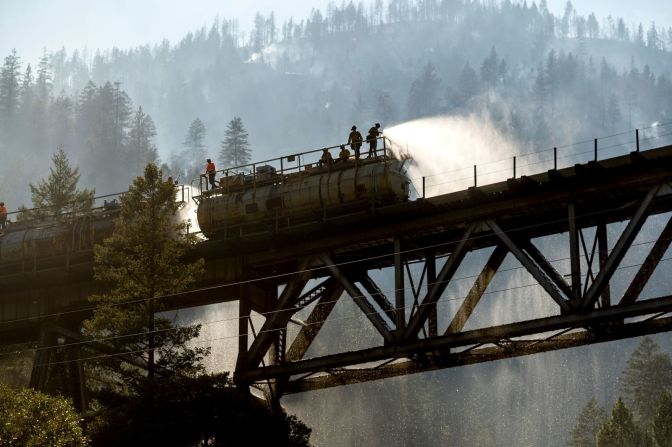 Los bomberos rocían agua del tren de bomberos de Union Pacific Railroad mientras luchan contra el incendio Dixie en el Bosque Nacional Plumas de California el 16 de julio. Foto de Noah Berger / AP