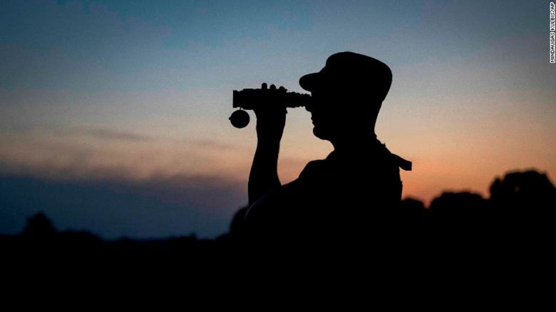 Un miembro del Servicio de Guardia de Fronteras de Lituania mira a través de binoculares mientras patrulla en la frontera con Belarús, cerca de la aldea de Purvenai, Lituania.