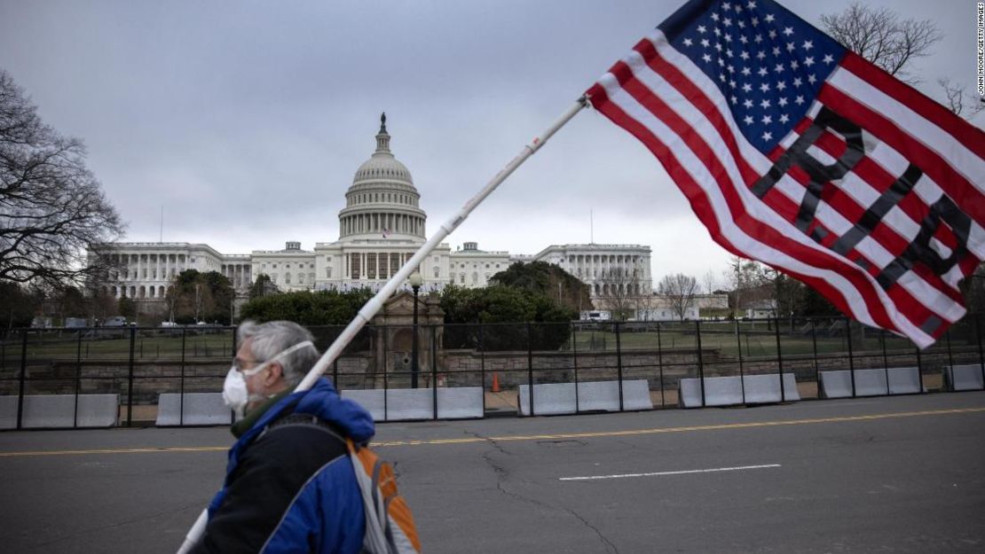 Un manifestante camina mientras la bandera estadounidense ondea a media asta en el Capitolio de Estados Unidos el 8 de enero de 2021, en Washington.