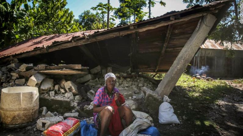 Una mujer frente a una casa destruida tras el terremoto.
