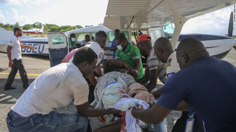 Un grupo de personas transfieren a una mujer herida a un avión que va rumbo a Puerto Príncipe en Haití.