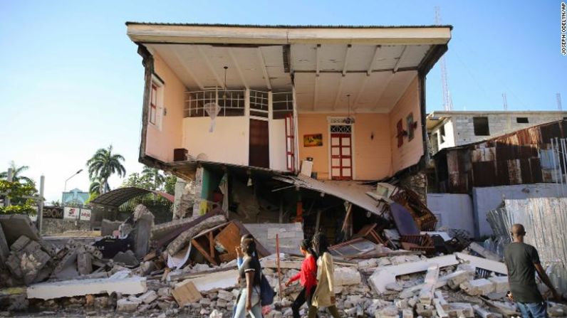 La gente pasa junto a una casa destruida por el terremoto en Les Cayes, Haití, el sábado 14 de agosto de 2021. Un terremoto de magnitud 7,2 sacudió Haití el sábado, con el epicentro a unos 125 kilómetros al oeste de la capital de Puerto Príncipe, dijo el Servicio Geológico de Estados Unidos.