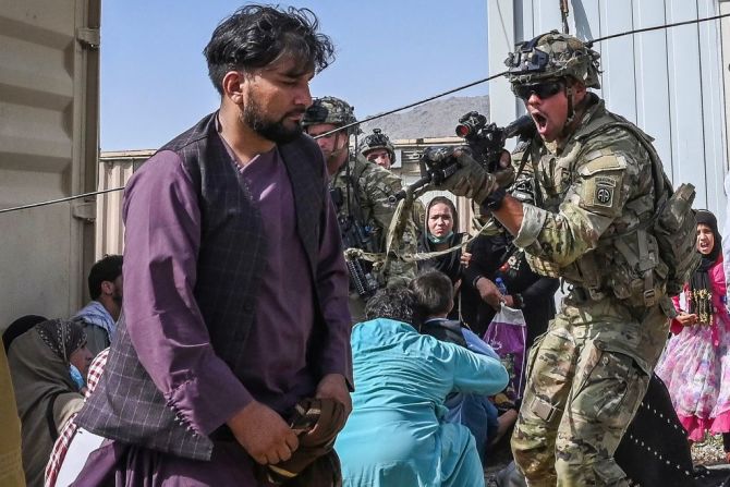 Un soldado estadounidense apunta su arma hacia un pasajero afgano en el aeropuerto de Kabul, luego de que miles de personas ingresaran por la fuerza al lugar intentando huir.