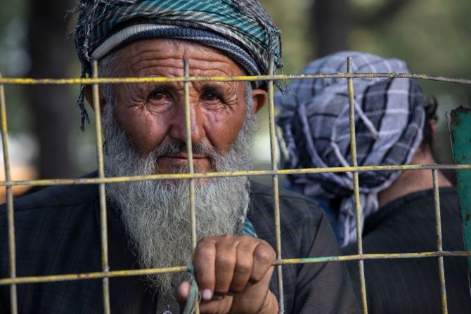 Charyar, de 70 años, mira a través de una reja desde un campamento de desplazados en Afganistán.