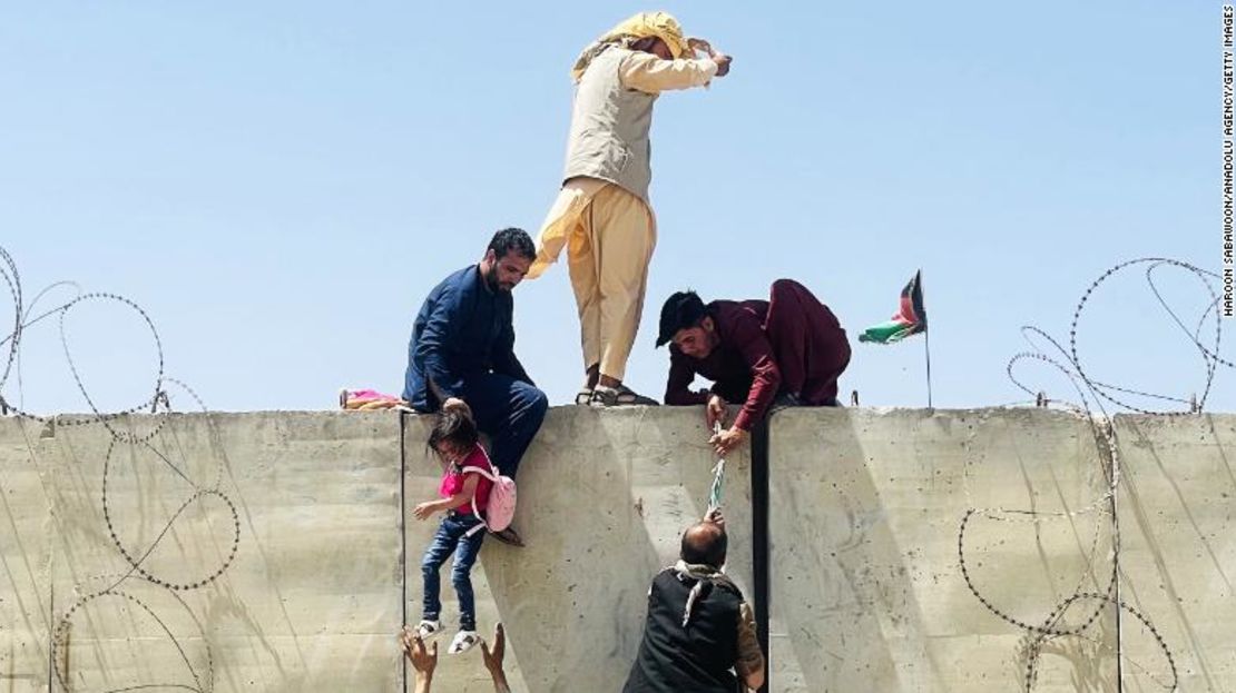 Los afganos escalan un muro alrededor del aeropuerto internacional Hamid Karzai durante la carrera para escapar de Kabul el lunes.