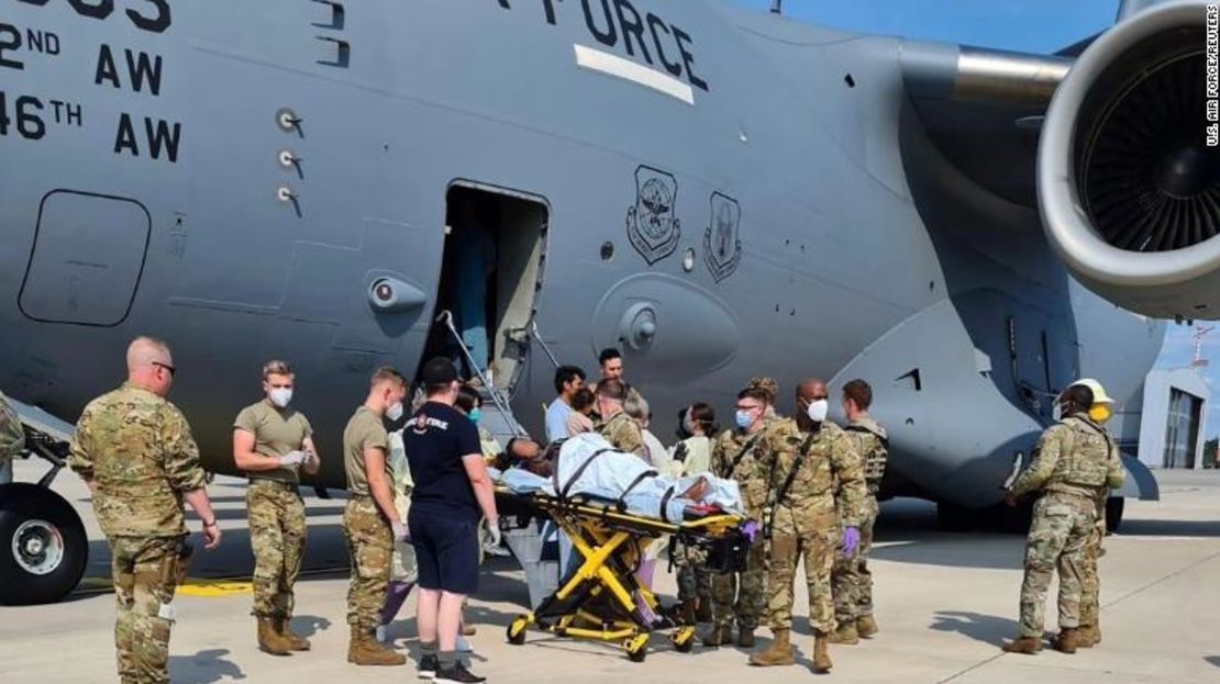 El personal de apoyo médico ayuda a una madre afgana, cuya identidad se ha ocultado digitalmente en la imagen, a bajar con su familia de un avión de transporte C-17 de la Fuerza Aérea de Estados Unidos, momentos después de haber dado a luz a una niña a bordo de la aeronave al aterrizar en la Base Aérea de Ramstein, Alemania.