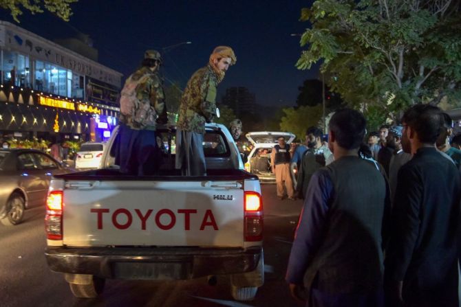 Soldados talibanes parados en una camioneta mientras voluntarios traen al hospital a los heridos por las explosiones.