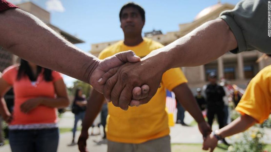 Manifestantes que protestan contra una nueva ley de inmigración se dan la mano en el Capitolio de Arizona el 23 de abril de 2010.