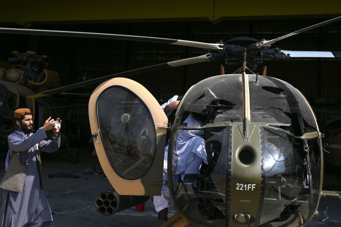 Un combatiente talibán toma una fotografía de un helicóptero MD 530 de las Fuerzas Aéreas afganas dañado en el aeropuerto de Kabul. Wakil Kohsar / AFP / Getty Images
