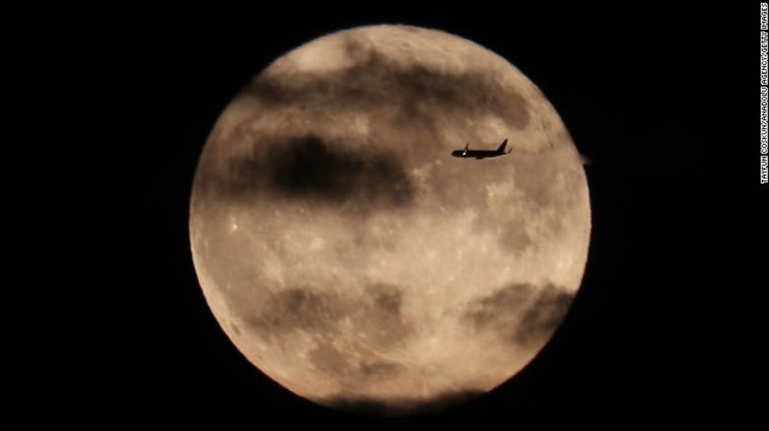 Un avión pasa por delante de la luna de la cosecha mientras se eleva detrás de la Estatua de la Libertad en la ciudad de Nueva York, el 1 de octubre de 2020.