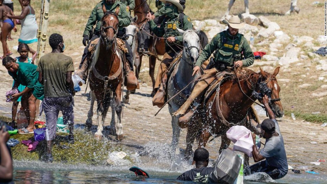 Agentes de la Patrulla Fronteriza a caballo tratan de impedir que migrantes haitianos entren en un campamento en las orillas del río Grande, cerca del puente internacional en Del Rio, Texas, el 19 de septiembre de 2021.