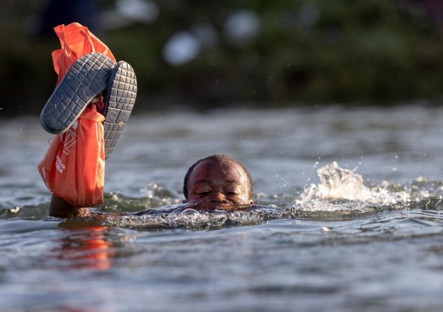 Un migrante lleva sus pertenencias por encima del agua mientras cruza el Río Grande de regreso a México.