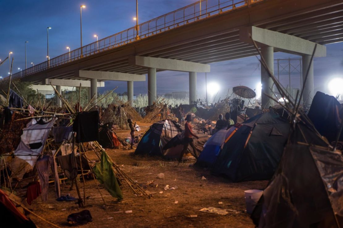 Un niño se baña con una jarra de agua dentro del campamento de migrantes en Del Río. Créditos: John Moore/Getty Images